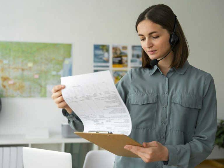 Woman in denim shirt reading documents in an office setting.