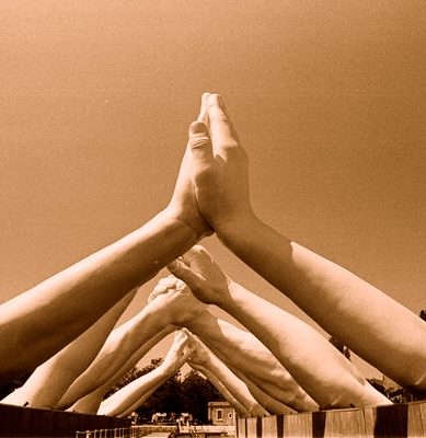 Multiple hands joining together in a team unity gesture, shown in black and white.
